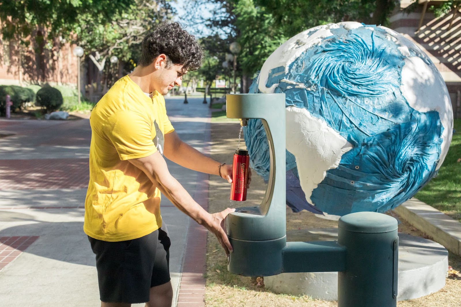 A student filling his water bottle at a water filling station.