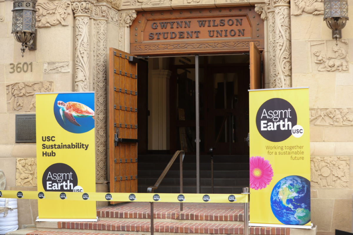 Entrance to the Gwynn Wilson Student Union building, with Assignment: Earth standing posters flanking the door and an uncut Assignment: Earth ribbon across the entrance.