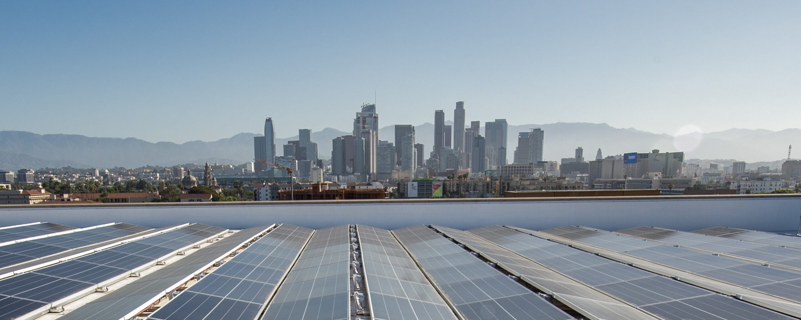 Solar panels on the roof of the Galen Center, with the Los Angeles skyline in the background.