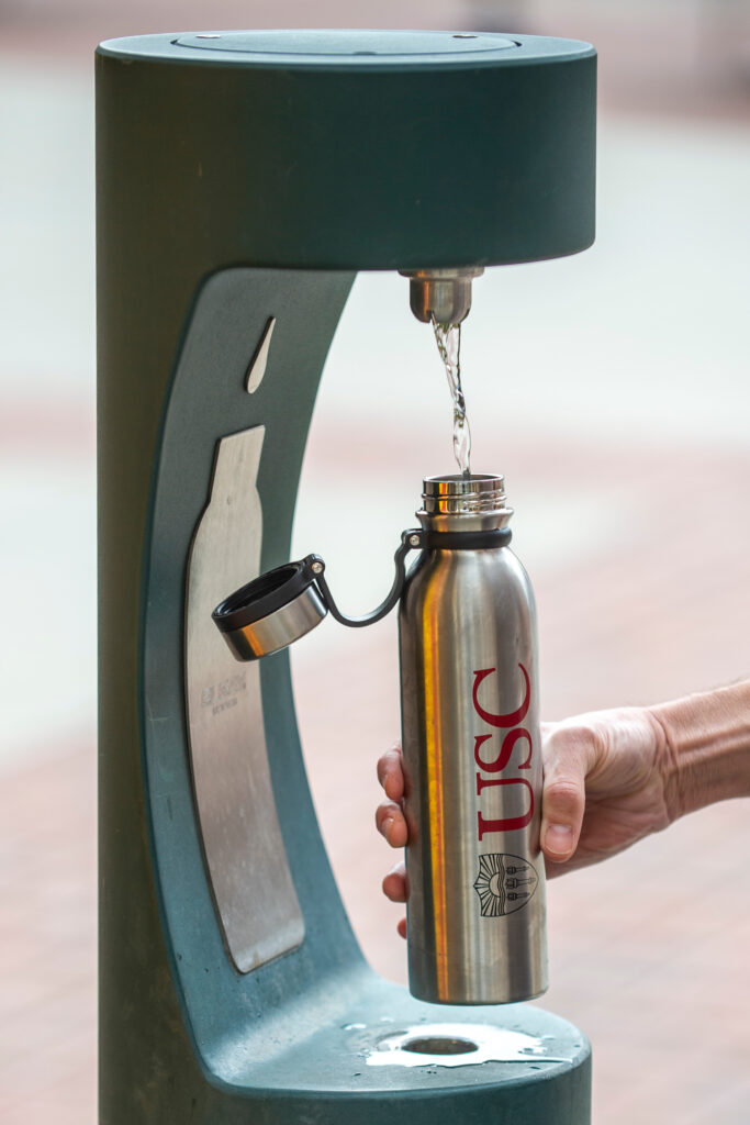Demonstration of a touchless water refill station installed outdoors at the Village using a USC branded stainless steel water bottle.