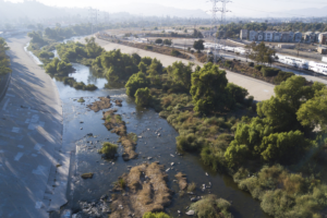 The Los Angeles River with rushing water and greenery.