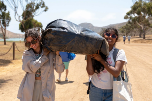 USC Ph.D. students Shayna Kohl (left) and Anvi Surapaneni (right), both from the lab of Professor Travis Williams, carry a discarded tire on Santa Catalina Island, where trash from the Great Pacific Garbage Patch often washes up. Photo credit: Vanessa Codilla