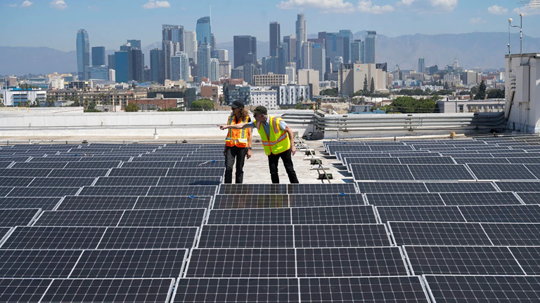 Zelinda Welch, USC’s director of energy and sustainability, and Campbell Odening, senior project manager, capital construction development, inspect newly installed solar modules atop the Carole Little Building. (USC Photo/Stephen Gee)
