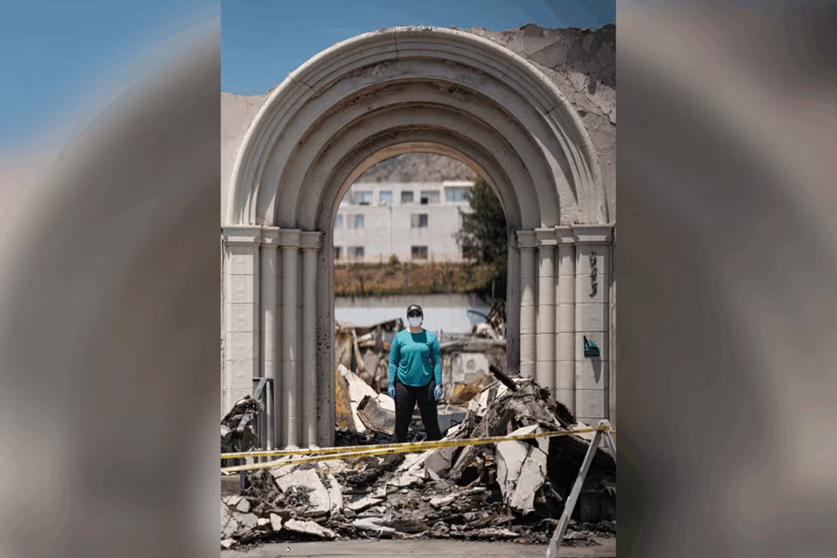 2025 Wrigley Institute Graduate Fellow Catherine “Cat” Odendahl stands underneath an archway in Altadena that withstood the destruction of the January 2025 L.A. wildfires, a symbol she believes conveys hope for the community (Nick Neumann/USC Wrigley Institute).